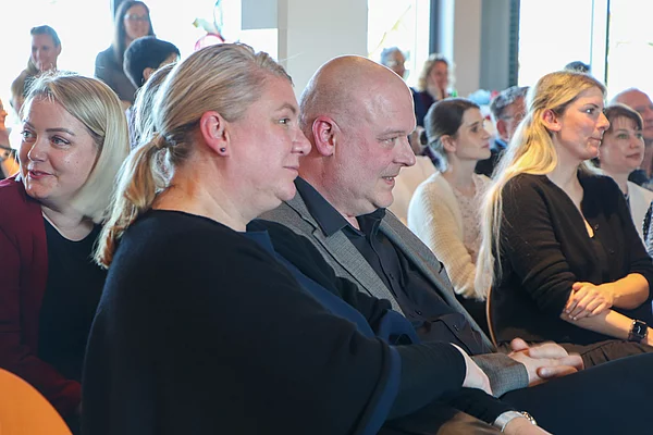 Ein Mann und eine Frau schauen auf die Bühne. Die Architektin und der Architekt.