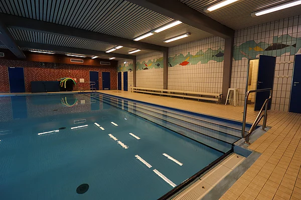 Ein Schwimmbecken. An der Wand sind Fische aus Fliesen angebracht