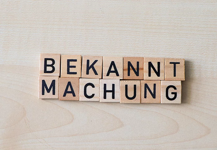 Holzplättchen formen das Wort Bekanntmachung