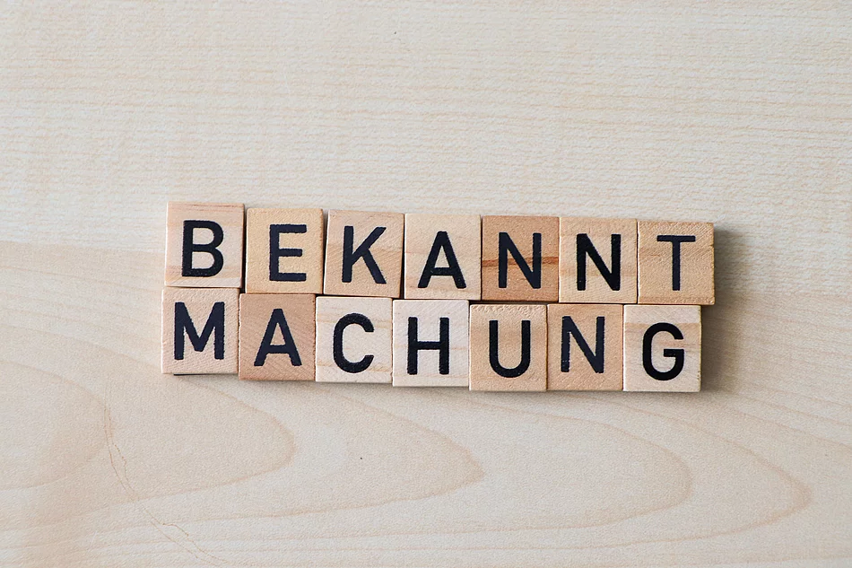 Holzplättchen formen das Wort Bekanntmachung