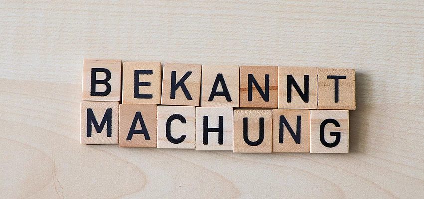 Holzplättchen formen das Wort Bekanntmachung