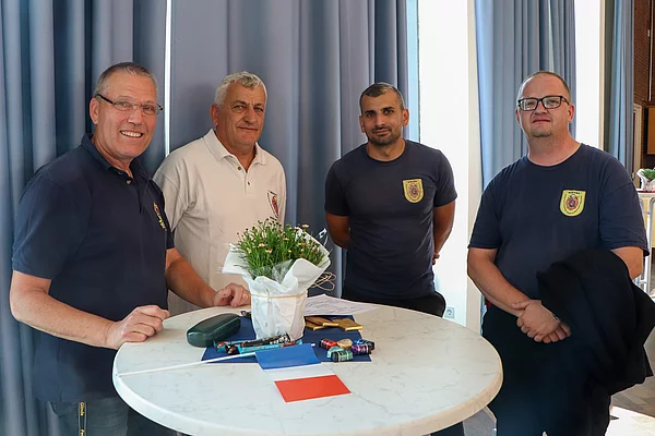Vier Feuerwehrmänner stehen an einem Tisch.