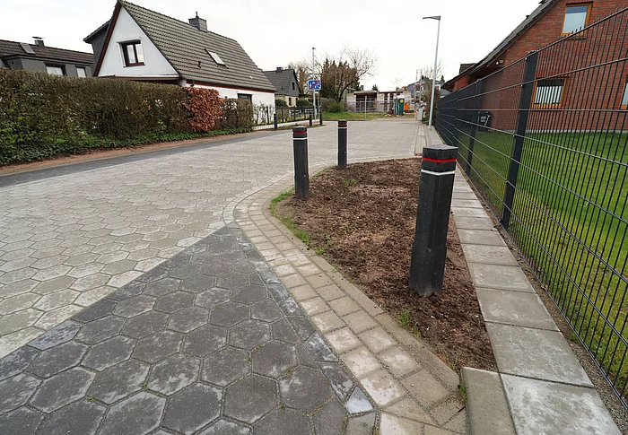 Blick auf die frischsanierte Starße "Großer Glinder Berg", die mit grauen und schwarzen Betonsteinen gepflastert ist.