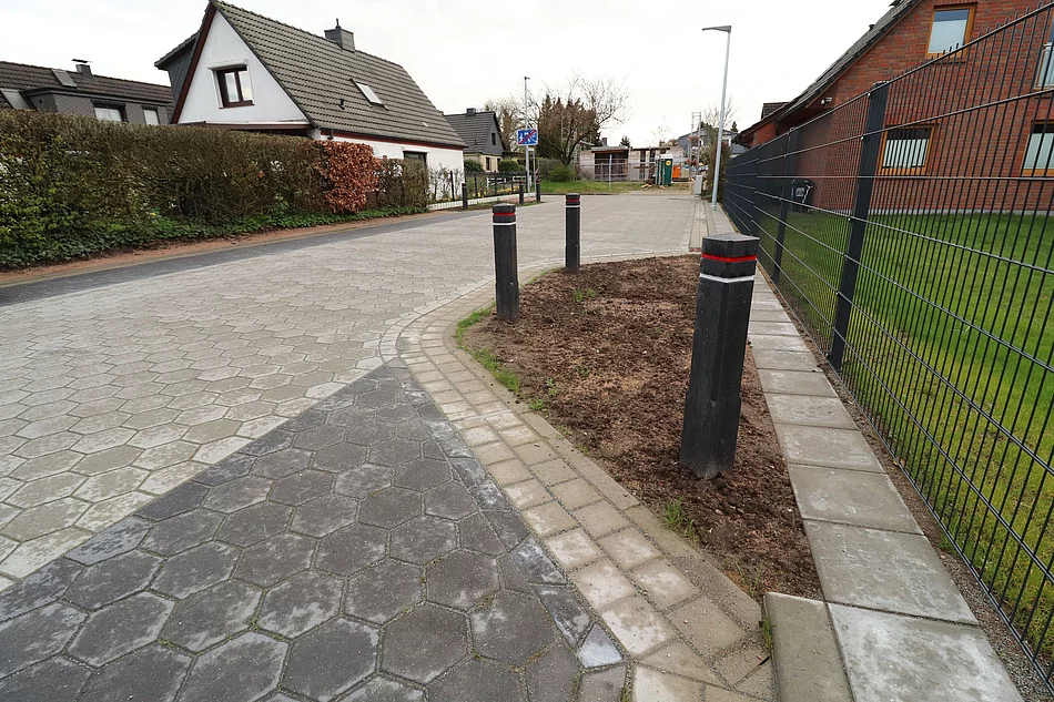 Blick auf die frischsanierte Starße "Großer Glinder Berg", die mit grauen und schwarzen Betonsteinen gepflastert ist.