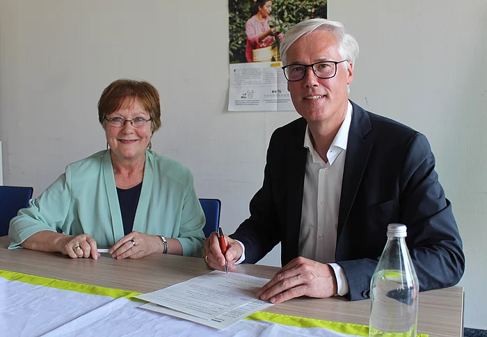 Ulrike Müller-Kopsch und Rainhard Zug unterzeichnen die Bewerbungsunterlagen als Fairtrade Town Foto: Stadt Glinde