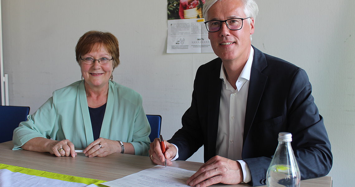 Ulrike Müller-Kopsch und Rainhard Zug unterzeichnen die Bewerbungsunterlagen als Fairtrade Town Foto: Stadt Glinde