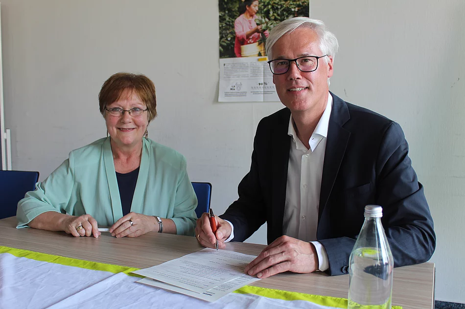Ulrike Müller-Kopsch und Rainhard Zug unterzeichnen die Bewerbungsunterlagen als Fairtrade Town Foto: Stadt Glinde
