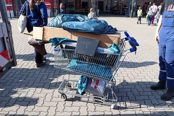 Ein kaputter Einkaufswagen ist voller Müllbeutel.